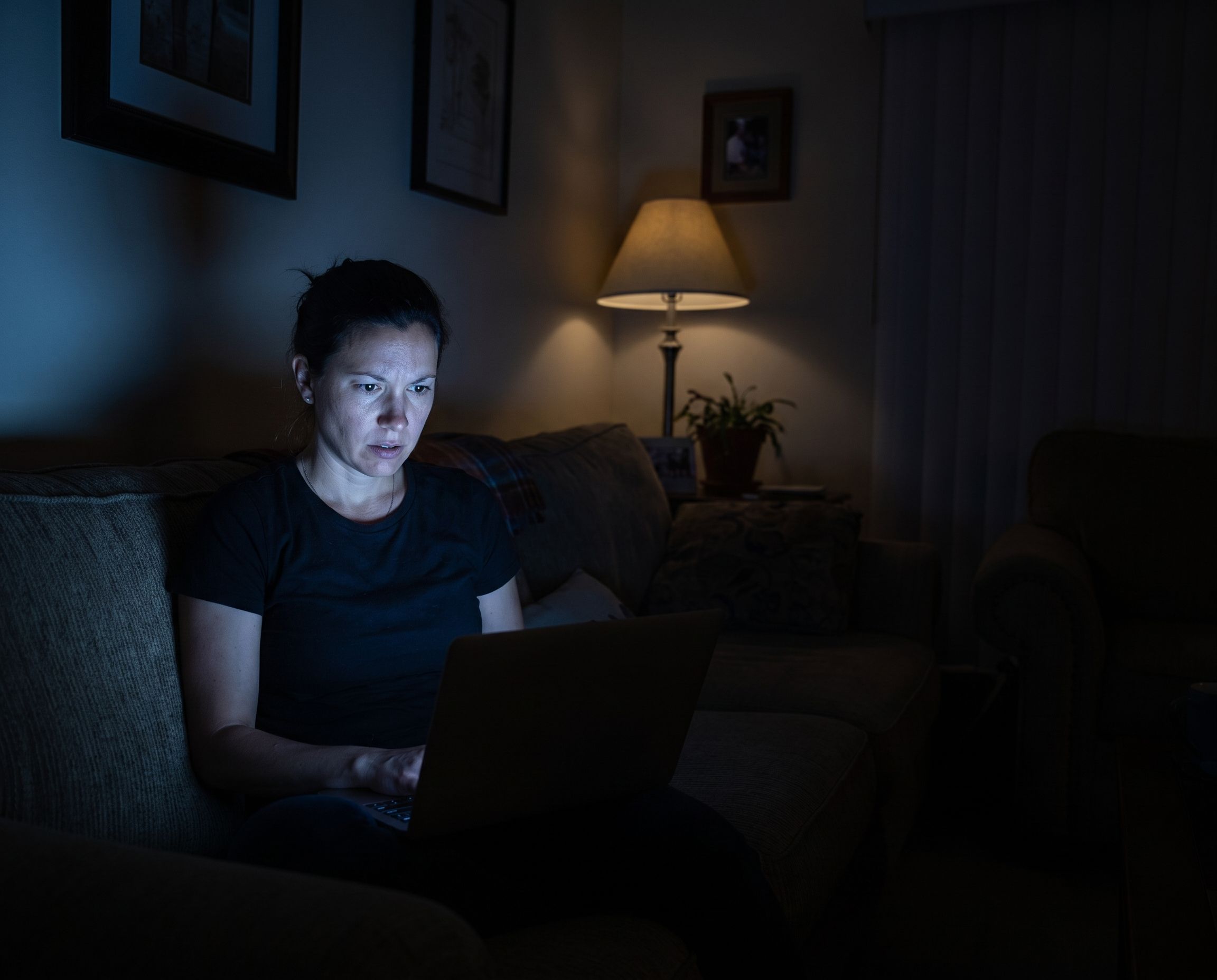 Freelancer trabajando solo de noche, iluminado únicamente por la pantalla de su laptop